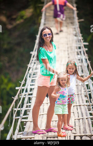 Kleine Mädchen und junge Frau, die zu Fuß auf der Hängebrücke über den Fluss Loboc, Philippinen Stockfoto