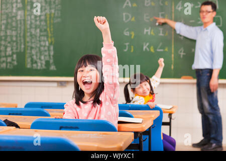 glückliche Schüler Hände erhebend, während des Unterrichts Stockfoto