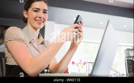 Lächelnde Geschäftsfrau hält Telefon suchen Stockfoto