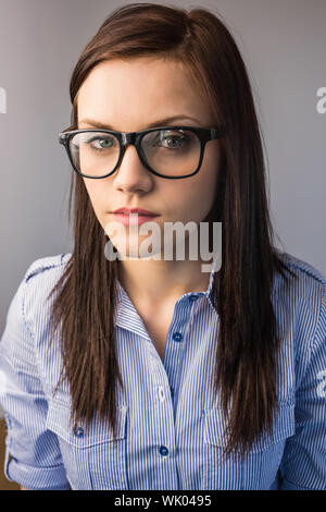 Ernsthafte hübsche Brünette mit Brille posiert Stockfoto
