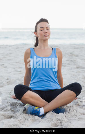 Sportliche Frau sitzt im sand Stockfoto