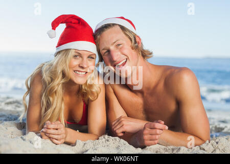 Paar am Strand tragen Weihnachtsmützen liegen Stockfoto