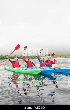 Glückliche Freunde auf See rudern Stockfoto