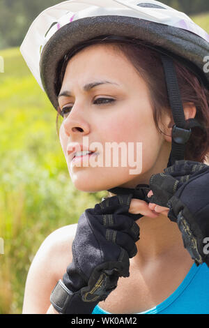 Sportliche Frau, die ihr Fahrradhelm anpassen Stockfoto