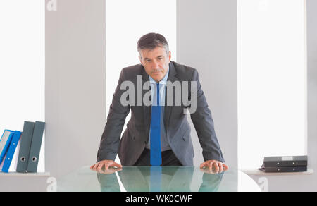 Stirnrunzelnd Geschäftsmann steht man vor einem Schreibtisch Stockfoto