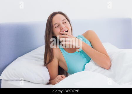 Verschlafene Frau Gähnen im Bett Stockfoto
