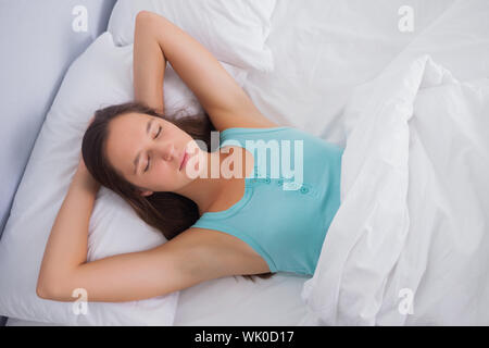 Brünette friedlich schlafend im Bett Stockfoto