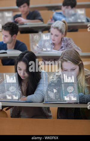 Studenten arbeiten an ihren digitalen Werkzeugen konzentriert Stockfoto