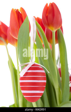 Bunte rote Ostern noch Leben mit zarten frischen Frühling Tulpen und Handbemalt traditionelle Ostereier angeordnet auf einem weißen Hintergrund mit copyspac Stockfoto