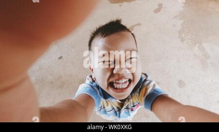 Der Junge war glücklich Verbreitung ein Regenschirm, glücklich lächelnd außerhalb Wandern. Stockfoto