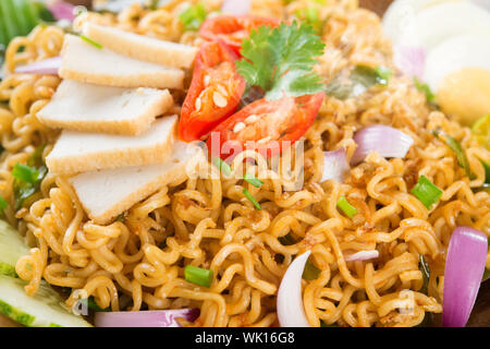 Close up Trocken Instant Noodle, malaysischen Stil maggi Goreng mamak oder würzigen trocken Curry Nudeln. Asiatische Küche, bereit, auf hölzernen Esstisch Tab zu dienen Stockfoto