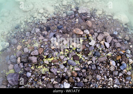 Schwefel zwischen den Felsen am Rand des vulkanischen Kratersee in Indonesien gesammelt Stockfoto