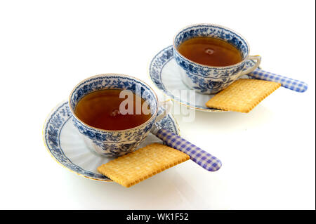 Zwei Porzellantassen und Untertassen mit Tee und Keksen Stockfoto