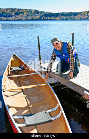 Mann hält Kanu am Dock am Lake of Two Rivers, Ontario, Kanada Stockfoto