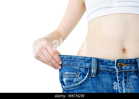 Fit junge Frau in loose Jeans nach Abnehmen isoliert auf weiss Stockfoto