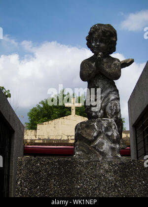 Ein Kreuz und die Engel Statue an der Chinesischen Norden Friedhof in Manila, Philippinen. Stockfoto