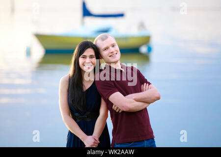 Glückliche junge interracial paar tatenlos zusammen See, bunte Boot im Hintergrund Stockfoto