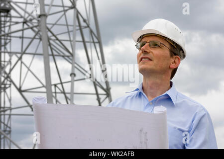 Ingenieur mit Blaupause vor Kran Stockfoto