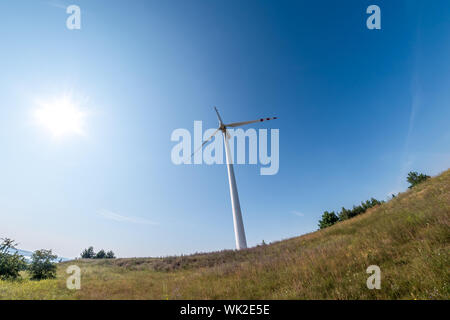 Drehende Flügel einer Windmühle Propeller auf blauen Himmel Hintergrund. Wind Power Generation. Reine grüne Energie. Stockfoto