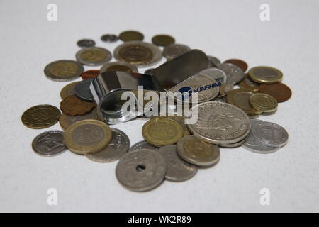 Nahaufnahme verschiedener internationaler Münzen mit einer Metallpfeife auf weißer Oberfläche; Konzept von Geld, Sparen, Sportfinanzierung oder Coaching-Finanzierung. Stockfoto