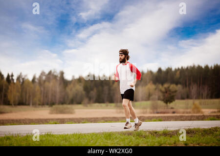 Ein Läufer mit langen Haaren und Bart Joggen im Land Stockfoto