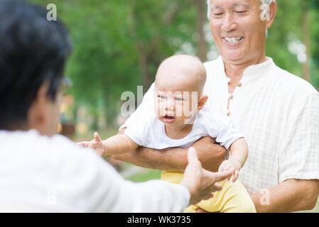 Asiatische Großeltern spielen mit Baby Enkel im Garten. Stockfoto