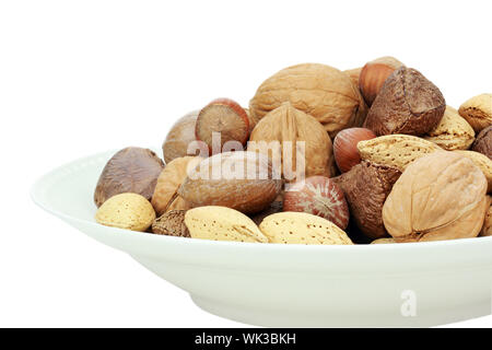 Eine Vielzahl von völlig gemischten Nüssen in der Schale vor einem weißen Hintergrund. Clipping-Pfad enthalten. Stockfoto