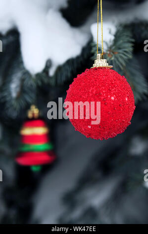 Weihnachtsschmuck hängen Schnee bedeckt Fichte außerhalb Stockfoto