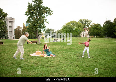 Familie spielen Frisbee, während mit Picknick im Park Stockfoto