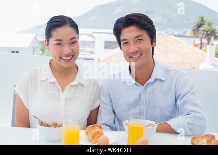 Lächelndes Paar zusammen frühstücken außerhalb auf einem Balkon Stockfoto