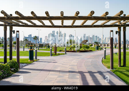 Traditionelle Holz- Eingang zum grünen Stadtpark von Corniche mit Blick auf die West Bay Skyline - Doha, Katar Stockfoto