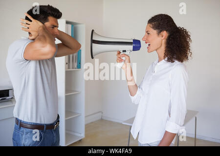 Casual Geschäftsfrau schrie Kollegen per Megaphon im Büro Stockfoto