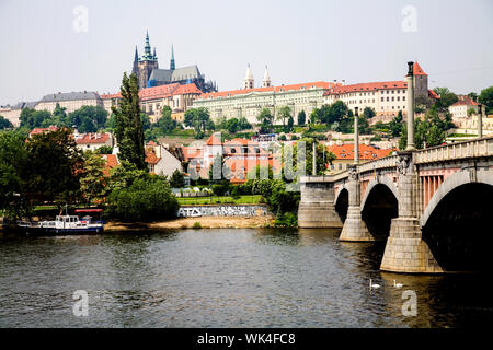 Die Moldau fließt unter Manesuv am meisten mit der Prager Burg (Prazsky Hrad) in der Ferne in Prag in der Tschechischen Republik Stockfoto