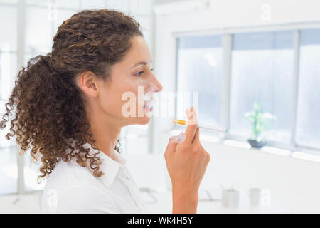 Casual Geschäftsfrau eine elektronische Zigarette rauchen im Büro Stockfoto