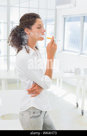 Casual Geschäftsfrau eine elektronische Zigarette rauchen im Büro Stockfoto