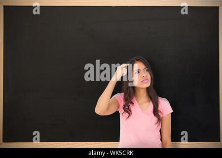 Hübsche brünette Denken gegen Schiefertafel mit Holzrahmen Stockfoto