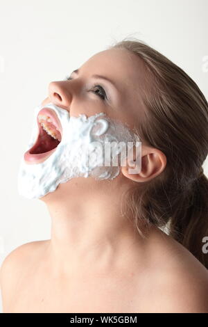 Gerne hübsche junge Frau mit weißen Bart machte der Rasierschaum auf weißem Hintergrund Stockfoto