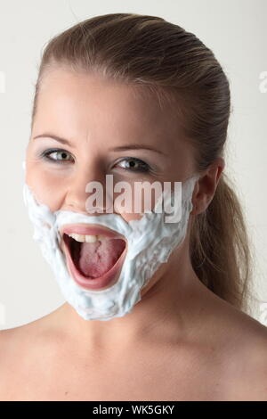 Gerne hübsche junge Frau mit weißen Bart machte der Rasierschaum auf weißem Hintergrund Stockfoto