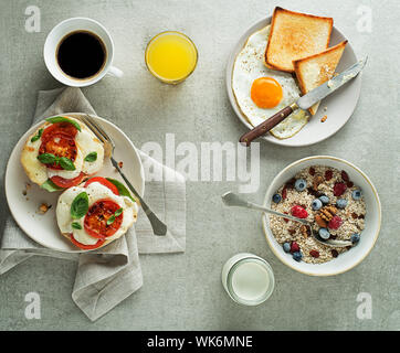 Frühstück serviert mit Haferflocken und Obst, Mozzarella Sandwich und Spiegelei mit Brot auf dem Tisch der Ansicht von oben. Gesundes Frühstück zu essen. Stockfoto