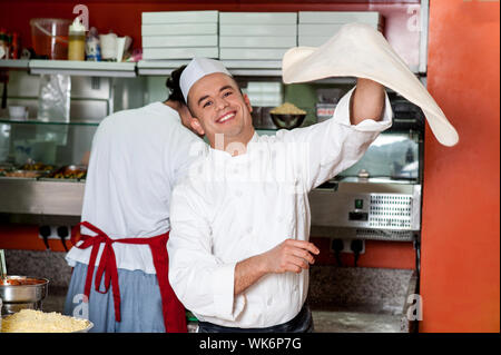 Koch macht den Pizzateig Drehung in der Luft Stockfoto