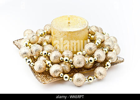 Auf weissem Hintergrund gold Kerze in einer Glasschale mit einem dekorativen String von Bomben isoliert. Stockfoto