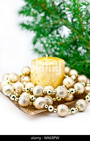 Die weiße Kerze mit einer Zeichenkette der Christmas Ball, ein Zurück Hintergrund tanne Zweig. Stockfoto