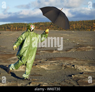 Die komische Person im schützenden wissenschaftliche Overall mit einem Regenschirm in der hand Stockfoto
