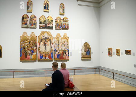 Junges Paar sitzt auf einer Ausstellungsfläche Altarbilder studieren von Jacopo di Cione und Workshop in der National Gallery, Trafalgar Square, London, UK Stockfoto