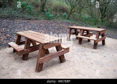 Zwei hölzerne Picknick-bänken auf einem Kies Base in einem Holz Stockfoto