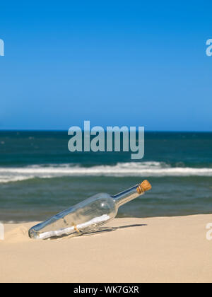 Eine Flasche mit einer Nachricht im Inneren wird am Strand begraben. Stockfoto