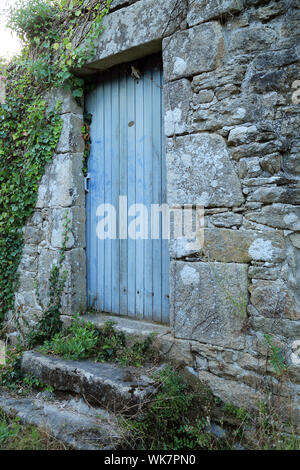 Graue Tür in Steinmauer mit Stufen (möglicherweise in Bourg) auf der Ile Aux Moines, Golfe du Morbihan, Bretagne, Frankreich Stockfoto