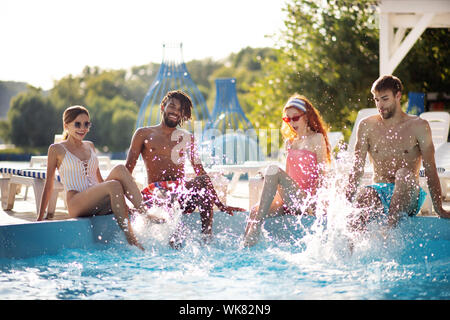 Paare Spritzwasser in den Pool, während Rest zusammen Stockfoto
