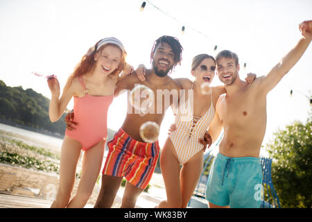 Freunde umarmen, während mit Seifenblasen in der Nähe des Flusses Kühlen Stockfoto