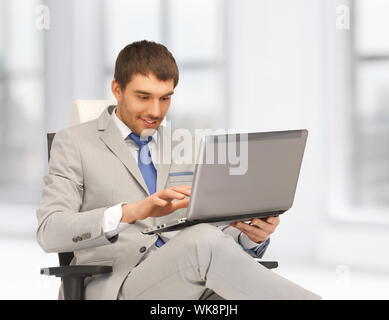 junger Geschäftsmann sitzt im Stuhl mit laptop Stockfoto